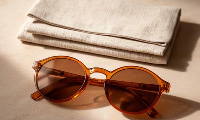 Bernsteinfarbene Sonnenbrille mit runder Form neben einer Leinenhülle